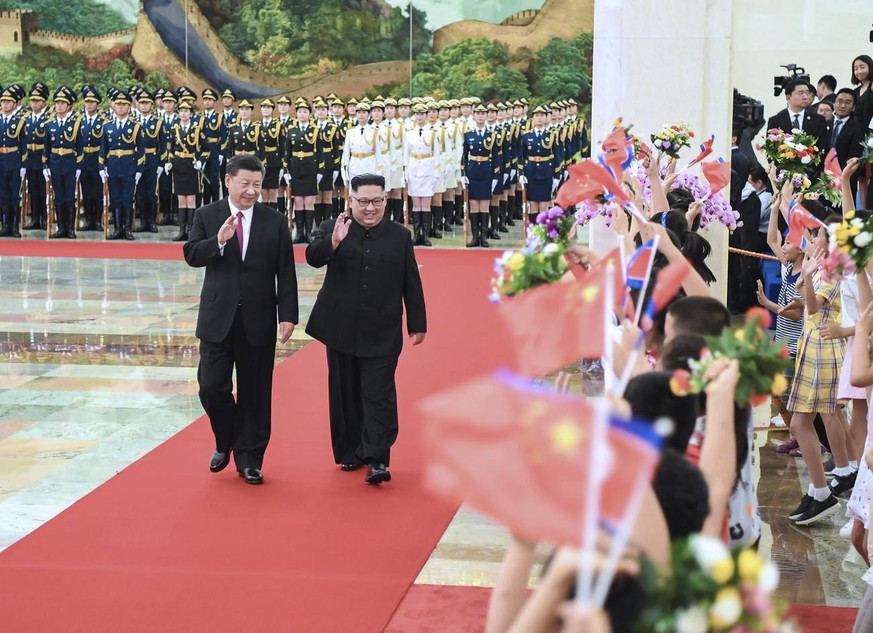 In this photo provided by China's Xinhua News Agency, Chinese President Xi Jinping, left, North Korean leader Kim Jong Un, right, walk together during a welcoming ceremony for Kim at the Great Ha ...