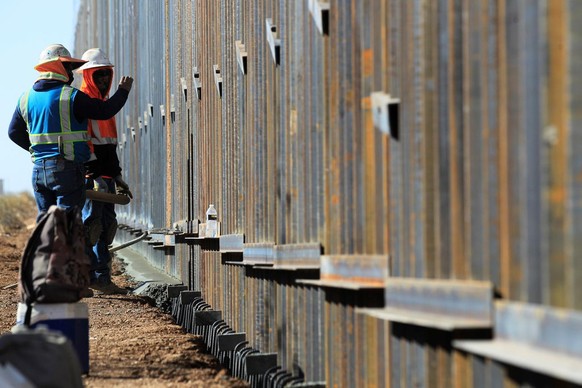 epa08858443 Workers from the Ultimate Concrete construction company speed up their task to finish the metal wall ordered by US President Donald J. Trump, on the border with Columbus County, New Mexico ...