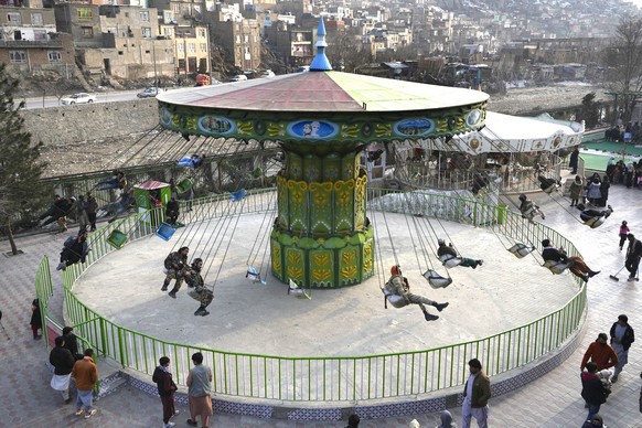 Taliban fighters with other Afghan men, ride a swing at an amusement park, in Kabul, Afghanistan, Friday, Feb. 18, 2022. (KEYSTONE/AP Photo/Hussein Malla)