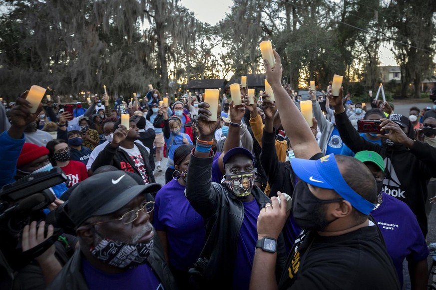 FILE - In this Feb. 23, 2021, file photo, Ahmaud Arbery&#039;s father, Marcus Arbery, bottom center, listens to Jason Vaughn speak during a memorial walk and candlelight vigil for Ahmaud at the Satill ...