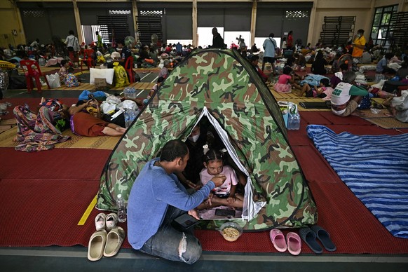 Evacuees eat breakfast as they take shelter in a gymnasium on the grounds of Surindra Rajabhat University in the Thai border province of Surin on July 25, 2025. More than 100,000 people have fled the  ...