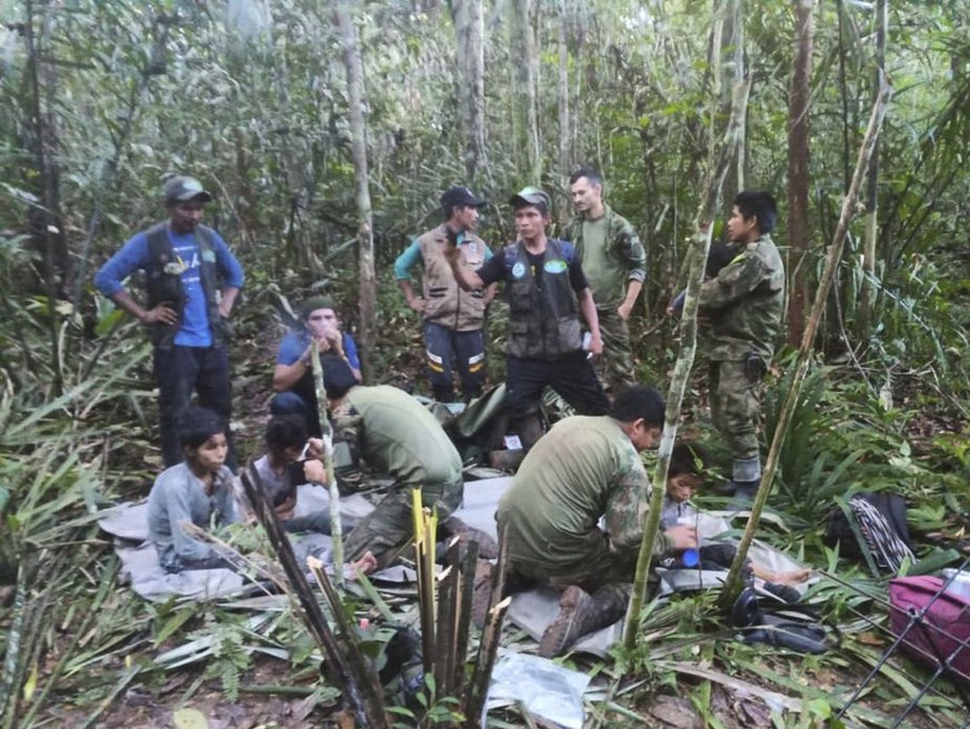 In this photo released by Colombia&#039;s Armed Forces Press Office, soldiers and Indigenous men tend to the four Indigenous brothers who were missing after a deadly plane crash, in the Solano jungle, ...