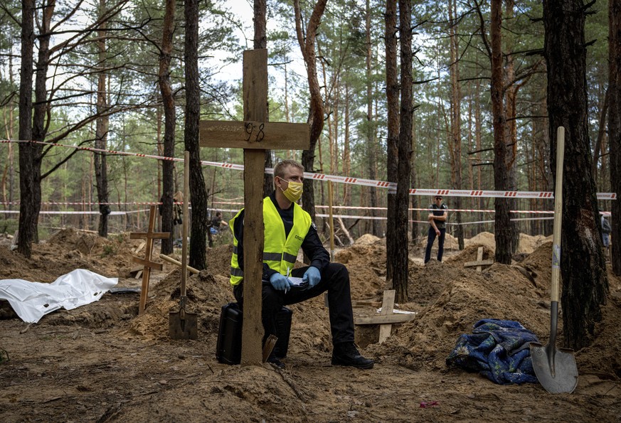 A police officer writes a protocol during an exhumation in the recently retaken area of Izium, Ukraine, Saturday, Sept. 17, 2022. Ukrainian authorities discovered a mass burial site near the recapture ...