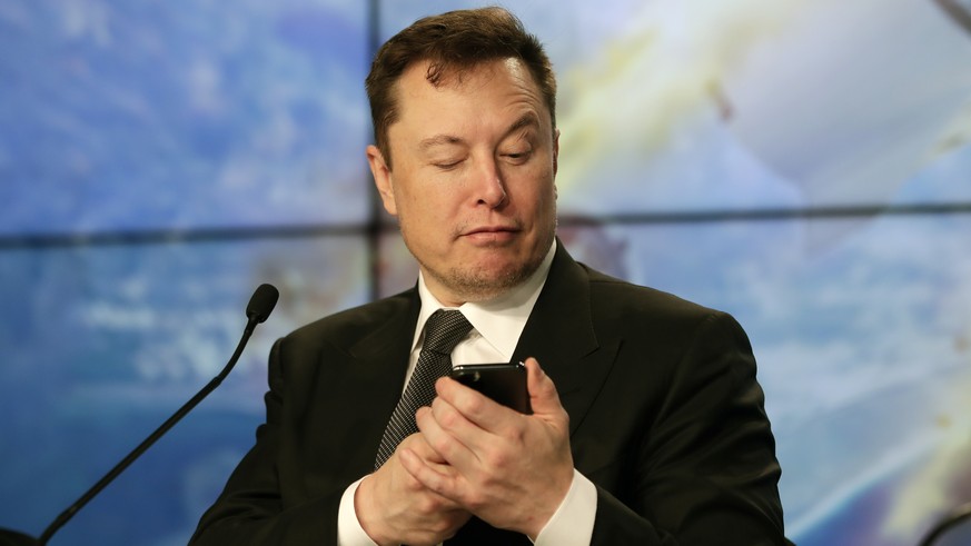 FILE - Elon Musk founder, CEO, and chief engineer/designer of SpaceX jokes with reporters as he pretends to search for an answer to a question on a cell phone during a news conference after a Falcon 9 ...