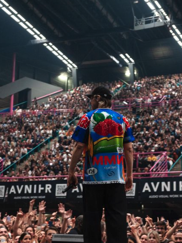 Orelsan portant l'un des vêtements de la collection «MMM». Les références à la Migros sont bien visibles.