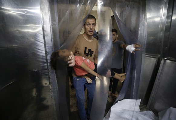 epa10908847 A Palestinian man carries a wounded child at Al-Shifa hospital in Gaza City, 09 October 2023. The Israeli army announced on 09 October, it carried out over 500 strikes on targets across th ...