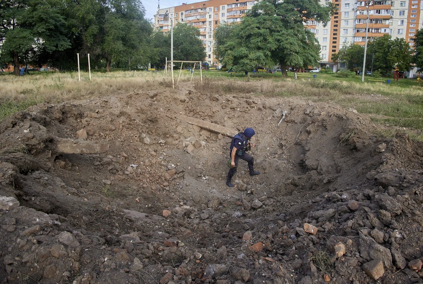 epa10092434 A policeman inspects a shelling crater in Kharkiv, Ukraine, 26 July 2022. Kharkiv and surrounding areas have been the target of heavy shelling since February 2022, when Russian troops ente ...