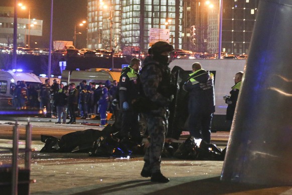 epa11237562 Russian emergency doctors collect bodies of victims near the burning Crocus City Hall concert venue following a shooting in Krasnogorsk, outside Moscow, Russia, 22 March 2024. A group of u ...