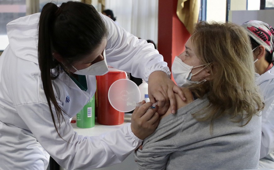 A woman gets her shot of the COVID-19 vaccine, in Quito, Ecuador, Thursday, Dec. 23, 2021. The government of Ecuador has declared COVID vaccination mandatory after a marked rise of infections and the ...