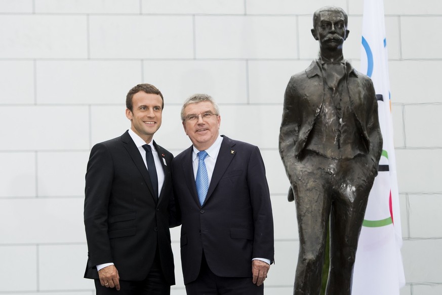 French President Emmanuel Macron, left, and International Olympic Committee, IOC, President Thomas Bach, right, from Germany, pose next to the Pierre de Coubertin statue, during a visit of the Paris 2 ...