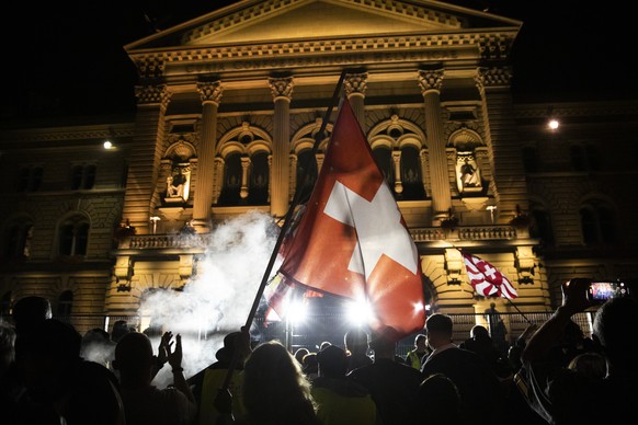 Demonstranten schwenken Fahnen hinter einem Zaun vor dem Bundeshaus auf dem Bundesplatz, waehrend einer Demonstration gegen die Massnahmen im Zusammenhang mit dem Coronavirus, am Donnerstag, 16. Septe ...