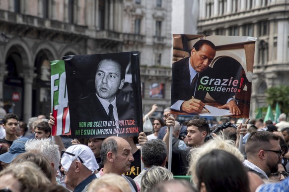 People hold posters with writing reading &quot;I didn&#039;t choose politics, it was imposed on me by history&quot;, left, and &quot;Thank you President&quot; gather in front of Milan&#039;s Gothic Ca ...
