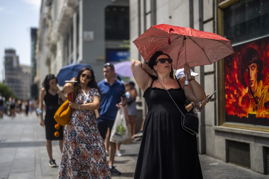 FILE - A woman holds an umbrella to shelter from the sun during a hot sunny day in Madrid, Spain, Monday, July 18, 2022. Europeans, particularly in the south of the continent, are being subjected to m ...