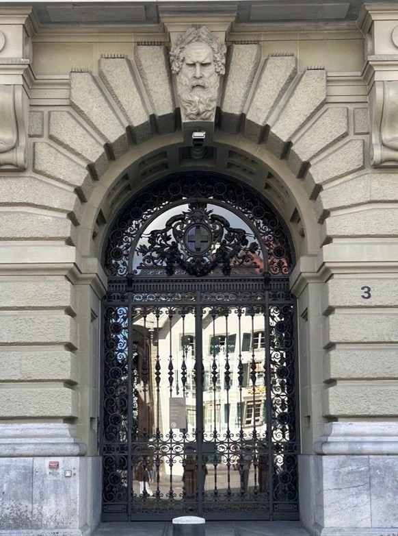L'entrée principale du bâtiment du Parlement, surplombée par le visage sévère du barbu.
