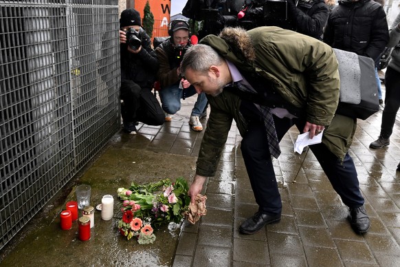 epa10513564 A man lays flowers and candles outside the crime scene a day after a deadly shooting in Hamburg, Germany, 10 March 2023. According to Hamburg authorities, at least eight people died, inclu ...