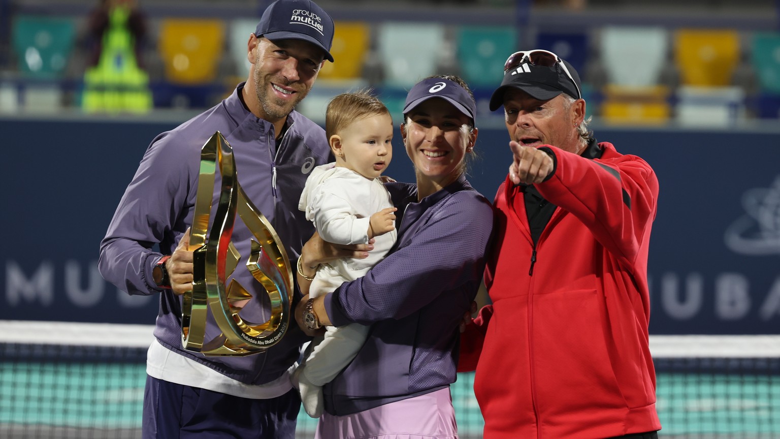 epa11882914 Belinda Bencic (C) of Switzerland poses with her husband (L) and coach (R) after winning her final match against Ashlyn Krueger of the USA at the WTA Abu Dhabi Open tennis tournament in Ab ...