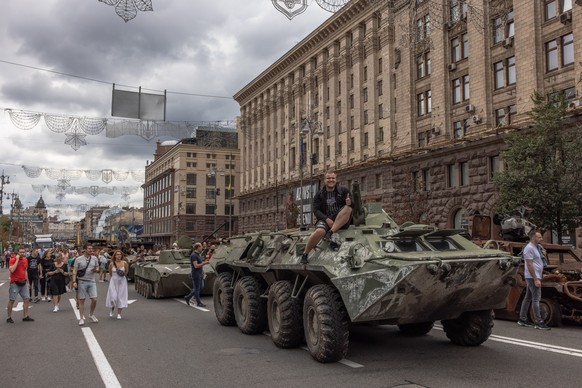 epa10130456 A man poses for photos on a Russian armoured personnel carrier that was damaged in fights with the Ukrainian army, displayed on Khreshchatyk street, in downtown Kyiv, ahead of the &#039;In ...