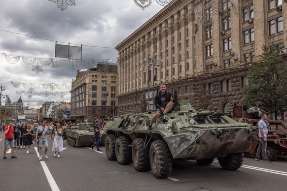 epa10130456 A man poses for photos on a Russian armoured personnel carrier that was damaged in fights with the Ukrainian army, displayed on Khreshchatyk street, in downtown Kyiv, ahead of the 'In ...