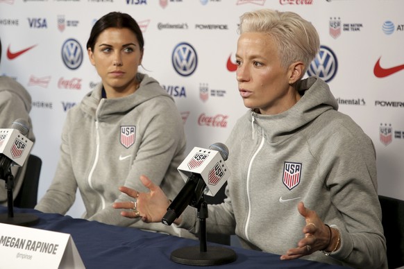 FILE - United States women&#039;s national soccer team member Alex Morgan, left, listens as teammate Megan Rapinoe speak to reporters during a news conference in New York, Friday, May 24, 2019. Megan  ...