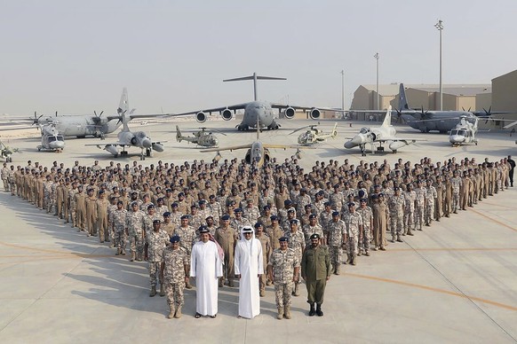 FILE - In this photo released by Qatar News Agency, QNA, the Qatari Emir Sheikh Tamim bin Hamad Al Thani, center front, poses for a photo with members of the Emiri Air Force at al-Udeid Air Base in Do ...