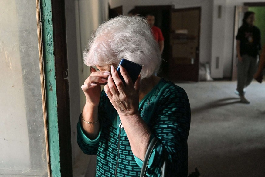 Une femme pleure en utilisant un téléphone portable dans un immeuble résidentiel endommagé suite à une attaque de drone russe.