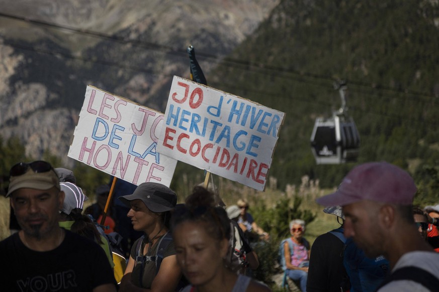 Frotest Planned Forest Clearing For 2030 Winter Olympics - Montgenevre Demonstrators carry signs defending the mountains and an ecological legacy. The CAOJOP 2030 organized the gathering at the Bois d ...