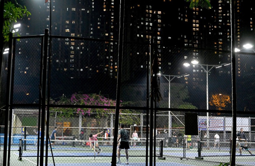 This picture taken on December 23, 2025 shows people playing pickleball in the playground of a residential area in Hanoi. The piercing pop-pop of pickleball paddles starts before sunrise and ends afte ...