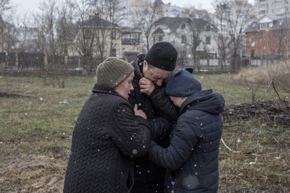 BUCHA, KYIV PROVINCE, UKRAINE, APRIL 03: A family grieve for a missing relative in front of a mass grave in the town of Bucha, on the outskirts of Kyiv, after the Ukrainian army secured the area follo ...