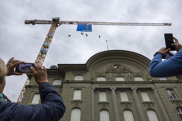 Greenpeace-Aktivisten entrollen am Swiss Overshoot Day auf dem Baukran auf der Baustelle der Nationalbank ein Transparent, am Samstag, 13. Mai 2023, auf dem Bundesplatz in Bern. (KEYSTONE/Peter Klaunz ...