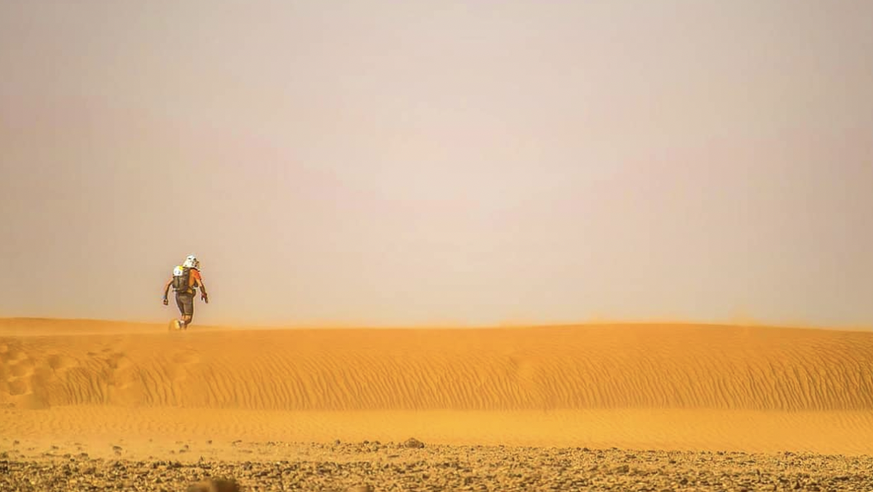 Un participant comme perdu dans l'immensité du désert marocain sous une chaleur écrasante.