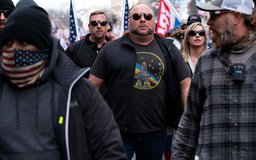 (FILES) In this file photo taken on December 12, 2020, US far-right radio show Alex Jones (C) joins supporters of US President Donald Trump in Washington, DC. - A US jury ordered conspiracy theorist A ...