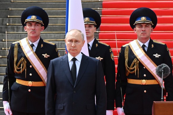 Russian President Vladimir Putin listens to the national anthem prior to delivering a speech to the units of the Russian Defense Ministry, the Russian National Guard (Rosgvardiya), the Russian Interio ...