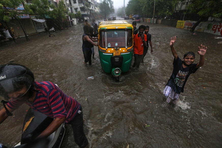 epa09209026 Indian people wade through a flooded street during heavy rainfall after the cyclone Tauktae hit in Ahmedabad, Gujarat, India, 18 May 2021. According to the India Meteorological Department  ...