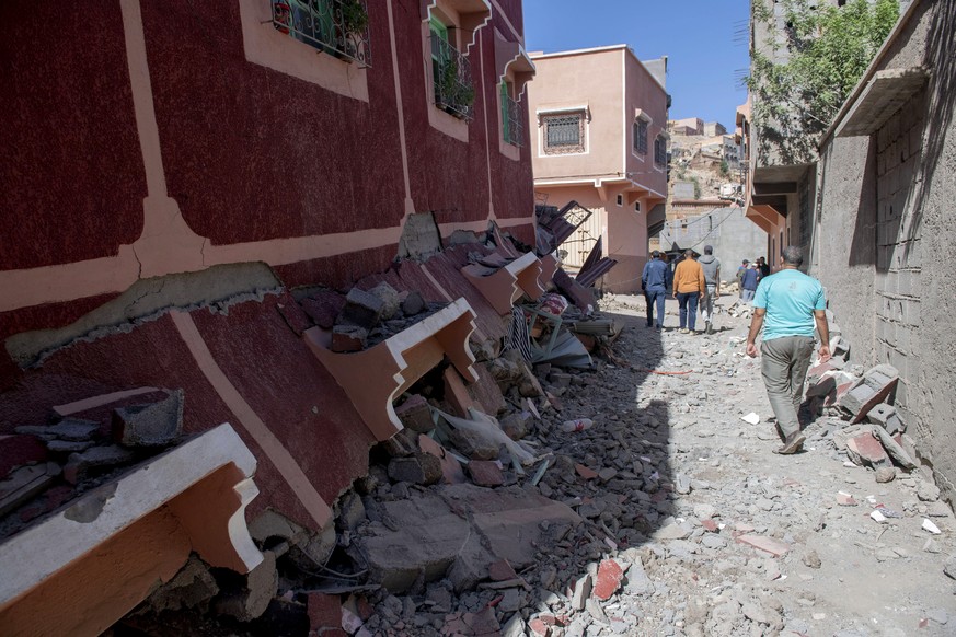 Des personnes marchent parmi les décombres d'un bâtiment endommagé à la suite d'un tremblement de terre à Marrakech.