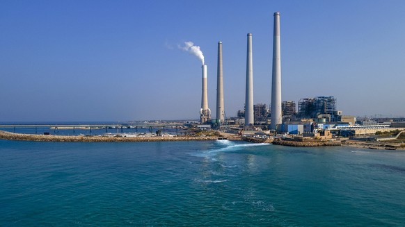 A person paddles on a board past Orot Rabin power station on the Mediterranean Sea near Hadera, Israel, Sunday, Nov. 6, 2022. Climate change, invasive species and explosive human activity are threaten ...
