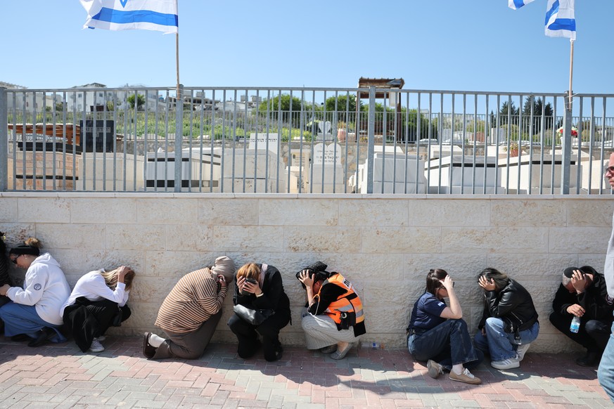 epa12789178 Mourners take cover as sirens sound during the funeral of Ronit Elimelech and Sara Elimelech, two of the victims killed in an Iranian airstrike the previous day, in Beit Shemesh, Israel, 0 ...