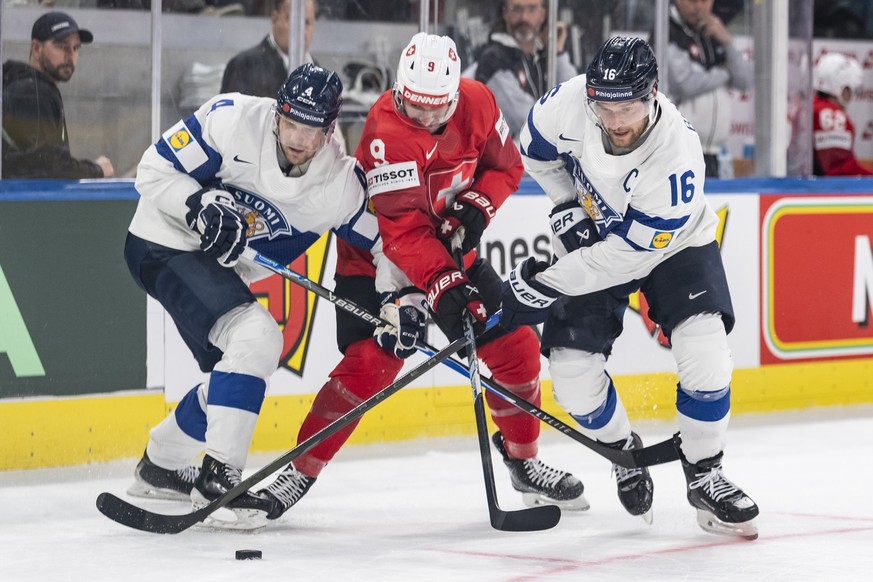 Switzerland's Damien Riat, center, vies for the puck with Finland's Mikko Lehtonen, left, and Aleksander Barkov, during the 2026 IIHF Men's Ice Hockey World Championship gold medal game ...