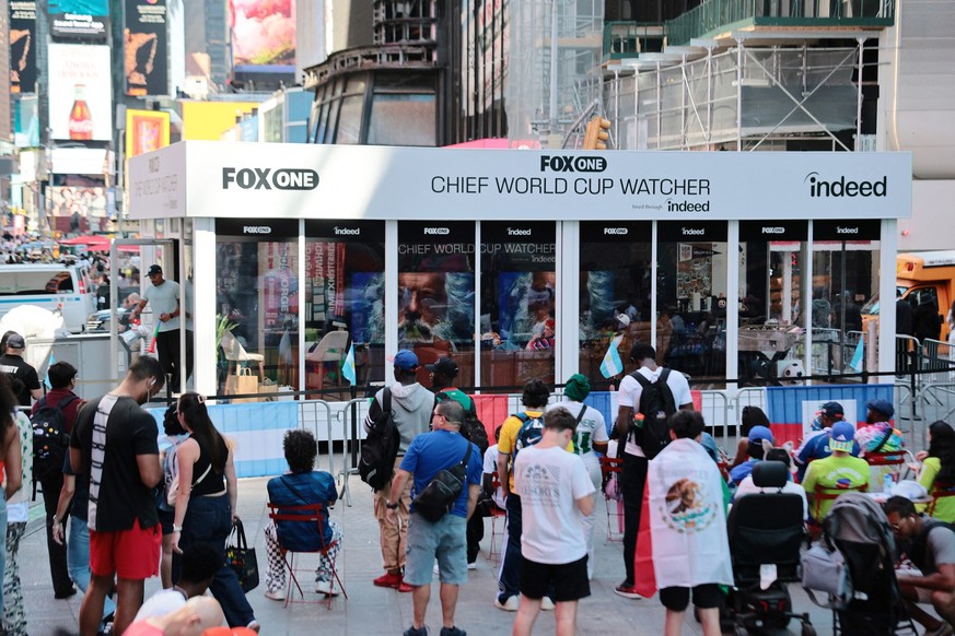 NEW YORK, NEW YORK - JUNE 16: People look on as Austin Franklin and Kevin Akoto, FOX One Chief World Cup Watchers, watch the Senegal versus France World Cup match in Times Square on June 16, 2026 in N ...