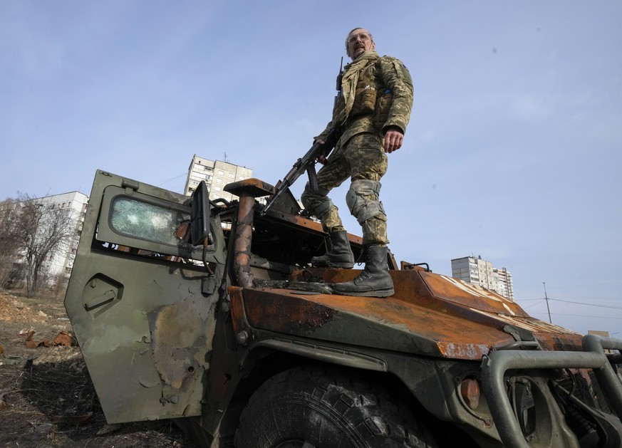 FILE - A Ukrainian soldier stands a top a destroyed Russian APC after recent battle in Kharkiv, Ukraine, on March 26, 2022. With Russia continuing to strike and encircle urban populations, from Cherni ...