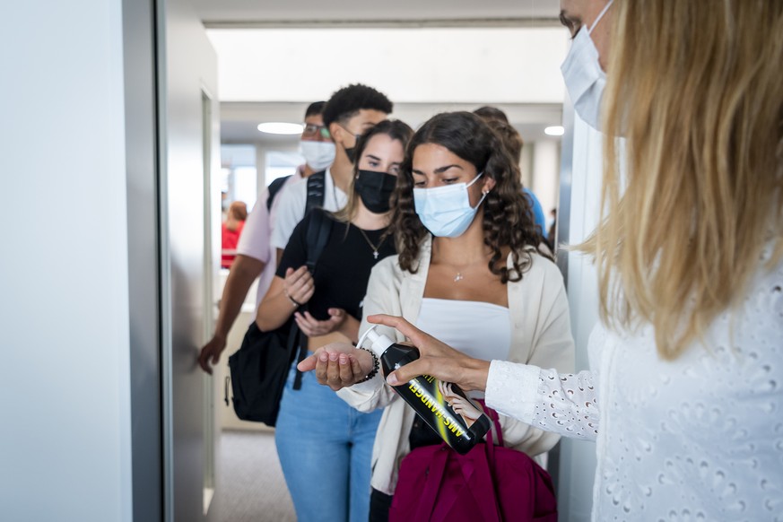 Une enseignante distribue du gel hydroalcoolique aux eleves portant un masque a l'entree d'une classe lors de la rentree scolaire dans le canton de Vaud le lundi 23 aout 2021 au Gymnase de B ...