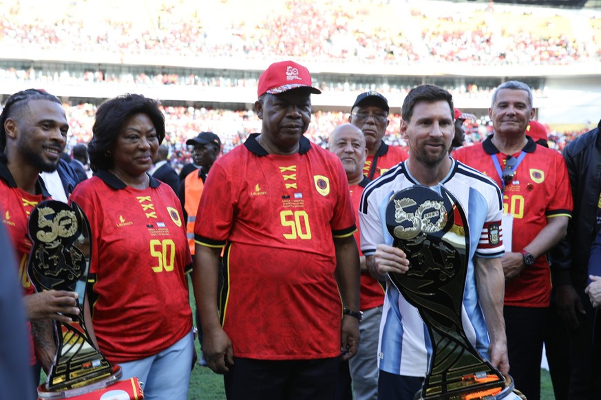 epa12526420 Lionel Messi (R) recieves a trophy next to Angola's President Joao Lourenco (C) and his wife Ana Dias Lourenco prior to the friendly soccer match between Angola and Argentina at the N ...