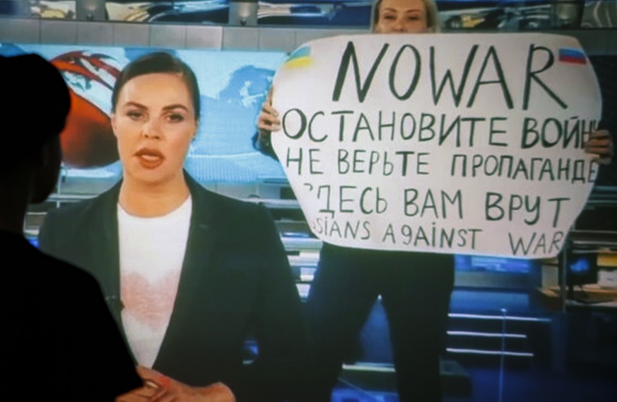 epa09826233 A woman watches a recorded feed of the Russian Channel One&#039;s evening news broadcast TV show in which an employee enters Ostankino on-air TV studio with a poster reading &#039;&#039;No ...