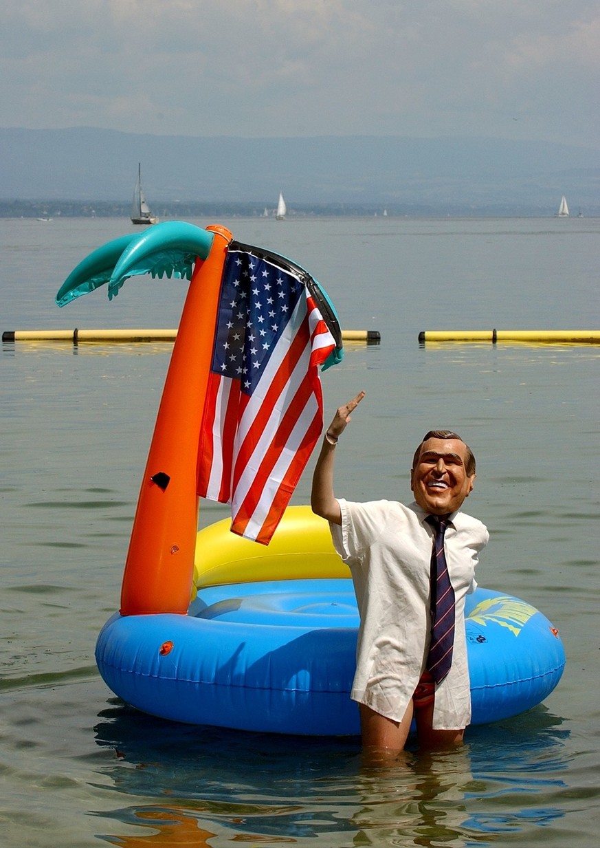 An activist of anti-globalisation group ATTAC Germany dressed as Bush, waves in front of a swimming island in the waters of lake Geneva, Saturday, May 31, 2003 in Geneva, Switzerland. Activists of Att ...