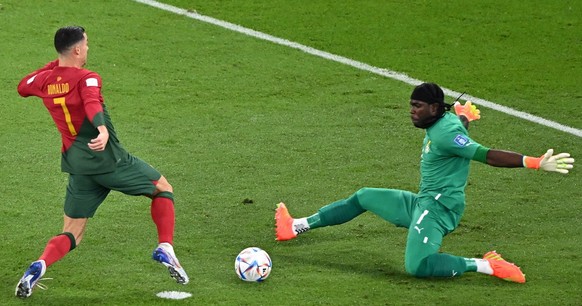 epa10325421 Cristiano Ronaldo (L) of Portugal in action against goalkeeper Lawrence Ati Zigi of Ghana during the FIFA World Cup 2022 group H soccer match between Portugal and Ghana at Stadium 947 in D ...