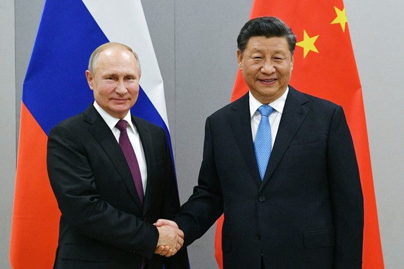 FILE - Russian President Vladimir Putin, left, and China&#039;s President Xi Jinping shake hands prior to their talks on the sideline of the 11th edition of the BRICS Summit, in Brasilia, Brazil in No ...