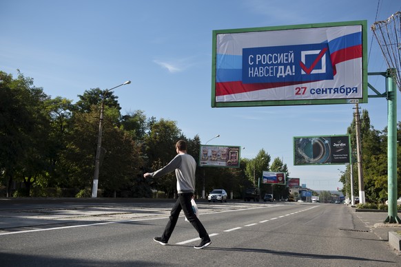 A man crosses a street with a billboard reading &quot;With Russia forever, September 27&quot; prior to a referendum in Luhansk, Luhansk People&#039;s Republic controlled by Russia-backed separatists,  ...