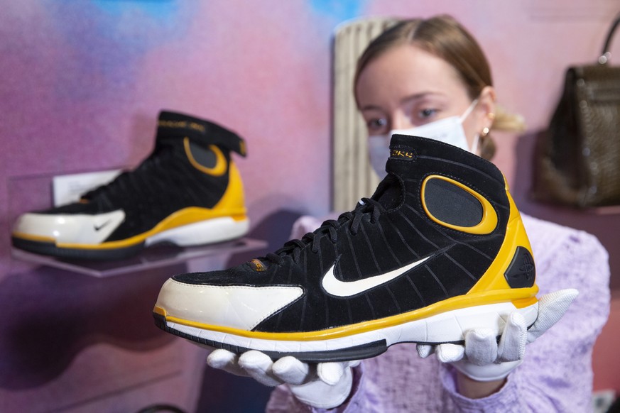 A Sotheby&#039;s employee holds a pair of Nike sneakers of worn in game by former NBA player Kobe Bryant, estimated to sell between 25&#039;000 - 35&#039;000 Swiss francs, during a preview at Sotheby& ...