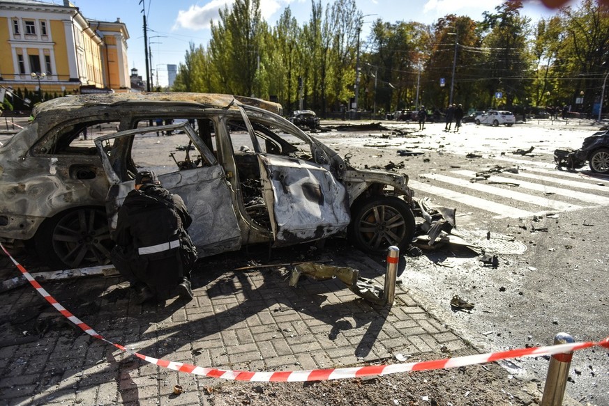 epa10234167 A criminal expert inspects a destroyed car at a site of shelling in downtown Kyiv (Kiev), Ukraine, 10 October 2022. Explosions have been reported in several districts of the Ukrainian capi ...