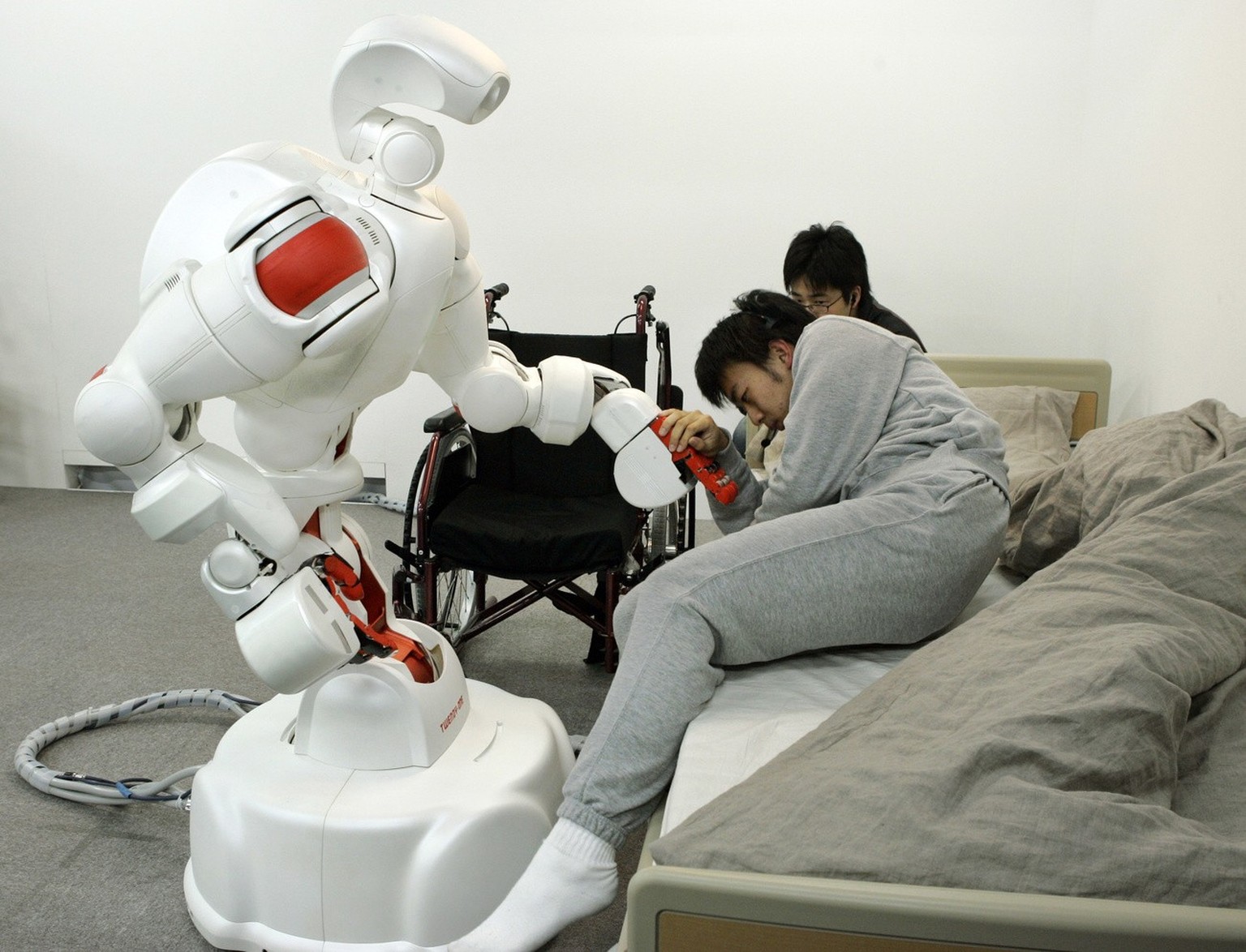 Humanoid robot Twendy-One gives a hand to assist Waseda University student Genki Fujii to move from his bed to a wheelchair during a demonstration of the robot designed to be safe to take care of elde ...