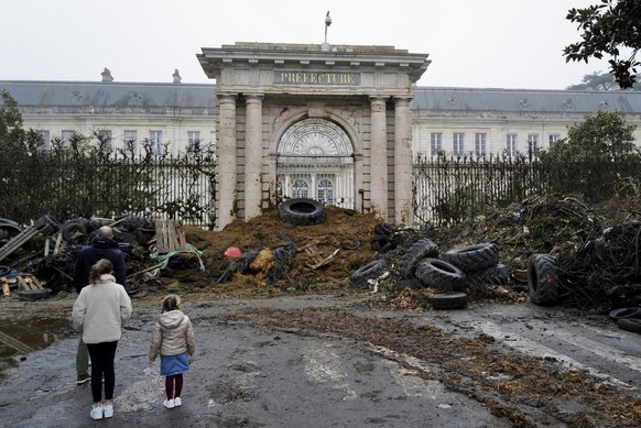 People watch slurry, manure and tyres dumped by farmers at the entrance of the local state administration building, in Agen, southwestern France, Saturday, Jan. 27, 2024. French farmers have vowed to  ...